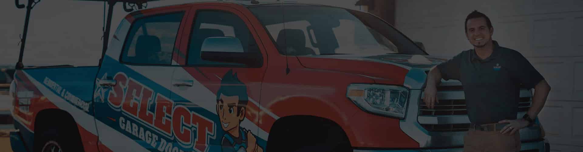 A man in a company polo shirt stands next to a red and white Select Garage Doors truck parked in front of a garage.
