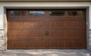Brown wooden garage door with vertical and horizontal paneling, decorative black hardware, and four small rectangular windows along the top.