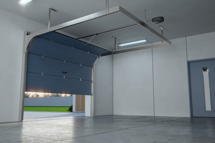 Interior of an empty garage with a partially open blue overhead door, gray concrete floor, and a door on the right wall.