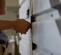 A person using a tool to unlock or repair a metal door or gate.