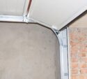 A partially open garage door with exposed brick and plaster walls visible inside and outside the garage.