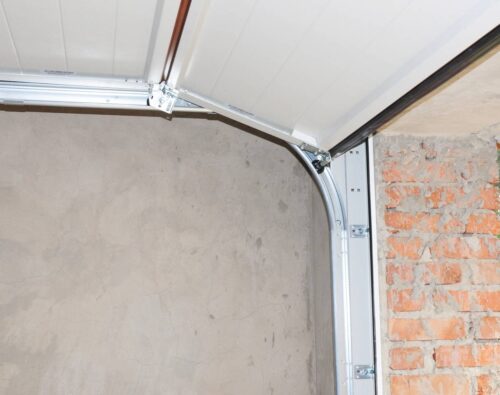 A partially open garage door with exposed brick and plaster walls visible inside and outside the garage.