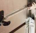 Close-up of a metal garage door lock mechanism with a handle and sliding bolt in the locked position.
