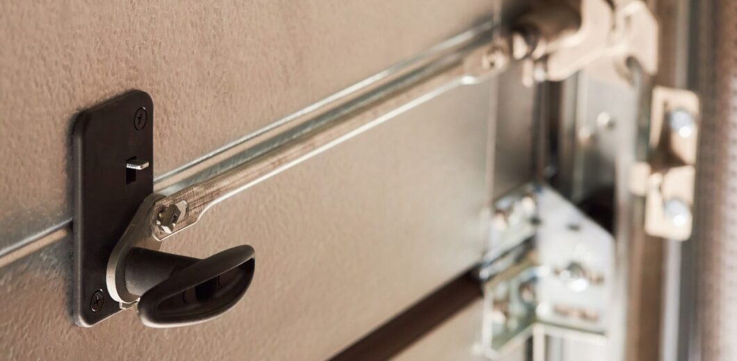 Close-up of a garage door lock mechanism with a black handle and metal rods securing the door.