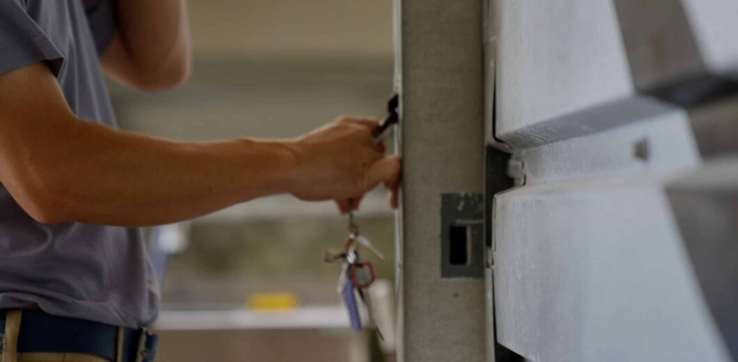 A person unlocking a metal door with a key, holding a set of keys in their hand.