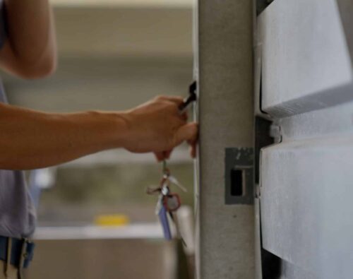 A person unlocking a metal door with a key, holding a set of keys in their hand.