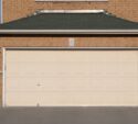 A closed beige double garage door attached to a brick house, with two lantern-style lights on either side and a concrete driveway in front.