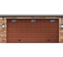 A closed brown wooden garage door with four small rectangular windows and two wall-mounted lantern-style lights on either side.