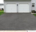 a residential asphalt driveway leading to a two-car garage